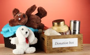 Donation boxes with clothing and food on red background close-up