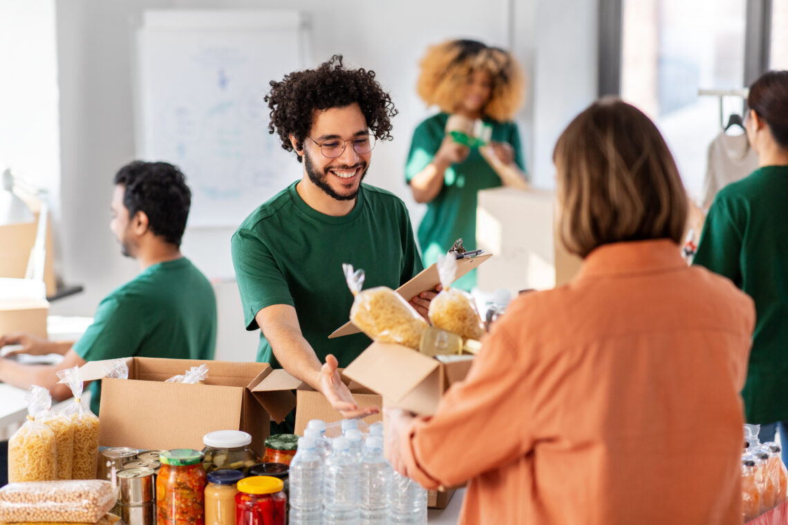 happy volunteers packing food in donation boxes