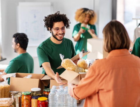 happy volunteers packing food in donation boxes