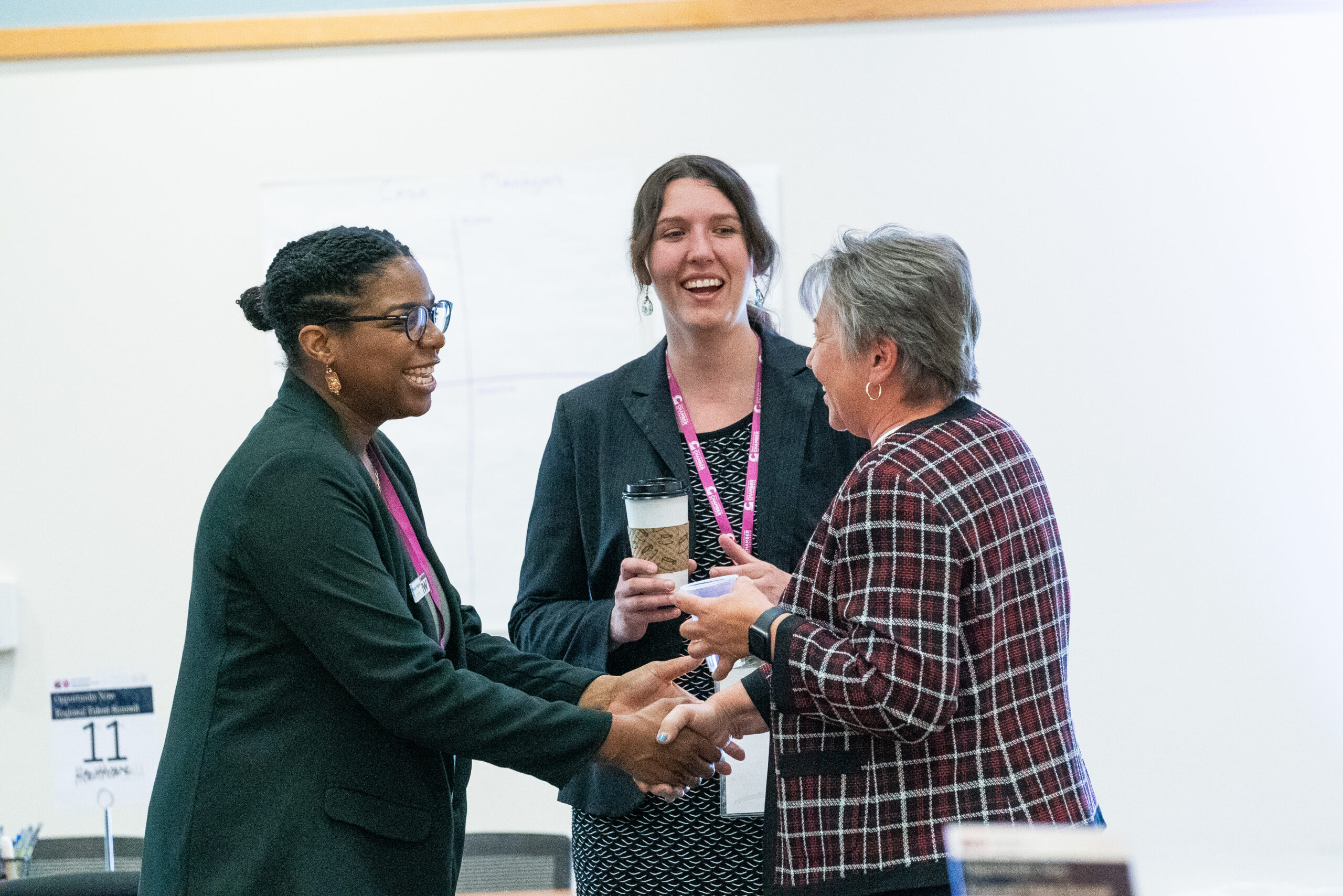 Three women shaking hands at talent summit.